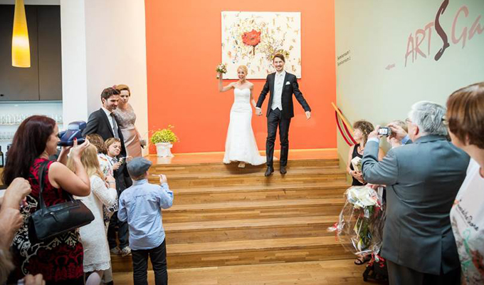 Brautpaar kommt die Stiegen von der Galerie herunter und wird von der Gästeschar fotografierend erwartet